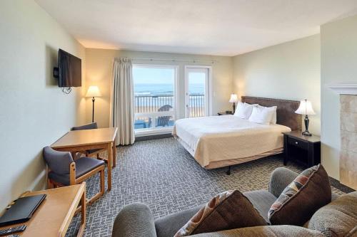 a hotel room with a bed and a balcony at Fireplace Queen Studio - Ocean View - Pool & Hot Tub in Lincoln City
