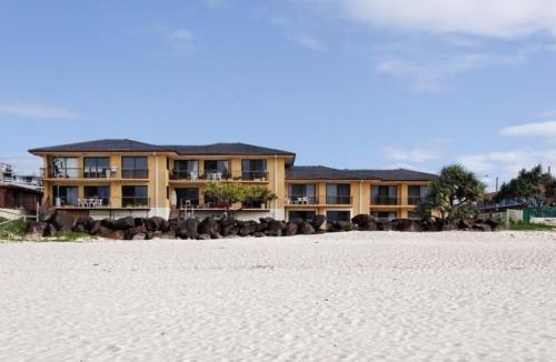 a large yellow building on the beach with the sand at Palm Breeze - Hosted by Burleigh Letting in Gold Coast