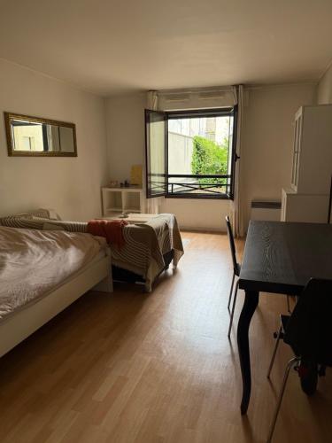 une chambre avec un lit, un bureau et une fenêtre dans l'établissement Appartement spacieux proche place République et Bastille, à Paris