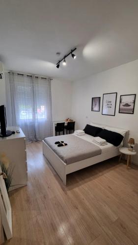 a white bedroom with a large bed and a table at La Daiana in Imola