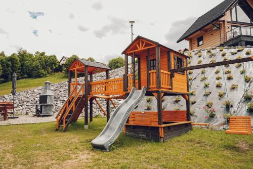 a playground with a slide next to a rock wall at Osada Kanada in Istebna