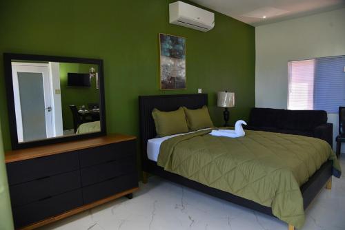 a bedroom with a large bed and a mirror at LS Stonethrow - Emerald Cottage in Montego Bay