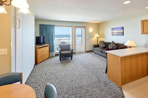 a living room with a couch and a chair in a hotel room at Corner Oceanview King Suite Full Kitchen Beach Access Pool & Hot Tub in Lincoln City