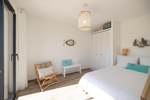 a bedroom with a white bed and a chair at Villa vacances Bassin d'Arcachon in Gujan-Mestras