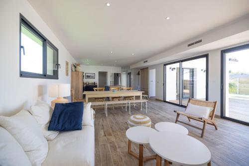 - un salon avec un canapé blanc, des tables et des fenêtres dans l'établissement Villa vacances Bassin d'Arcachon, à Gujan-Mestras
