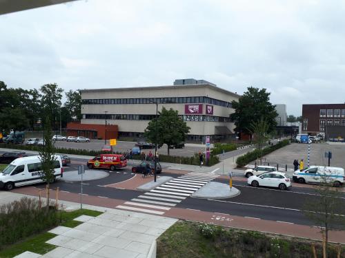 a large building with cars parked in a parking lot at Room in the center of Enschede in Enschede