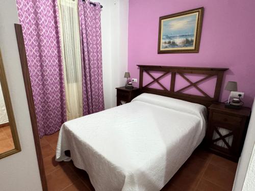 a bedroom with a white bed and purple walls at Chipiona Apartamento Bajo Centro Parking Incluido WiFi GRATIS in Chipiona