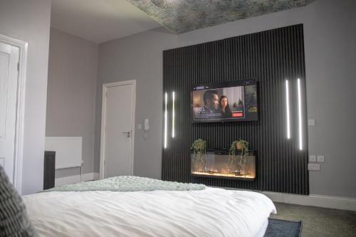 a bedroom with a bed and a tv on a wall at Check Inn 247 in Bradford