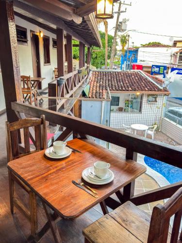 a wooden table with two cups and plates on a balcony at Pousada Mar de Porto in Porto Seguro