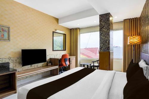 a hotel room with a bed and a flat screen tv at Super Collection O FRI Dehradun in Dehradun