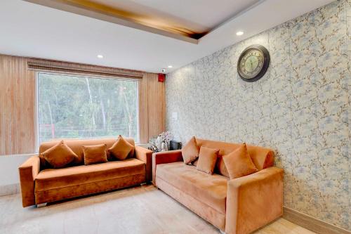 a living room with two couches and a clock on the wall at Super Collection O FRI Dehradun in Dehradun