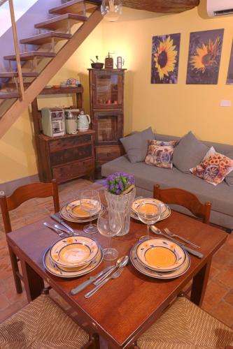a wooden table with plates and wine glasses on it at Il Respiro del Borgo in Civitella Del Lago