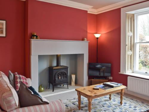 a living room with red walls and a fireplace at Shorley Lodge in Keswick