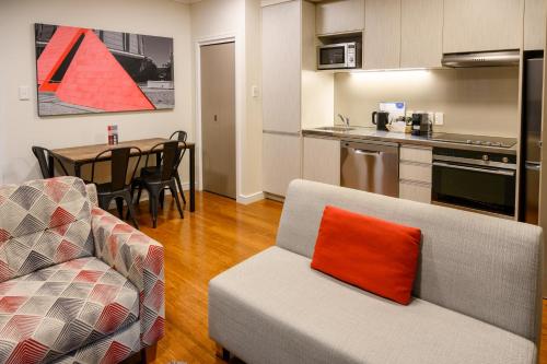 a kitchen and a living room with a couch and a table at Boulcott Suites in Wellington