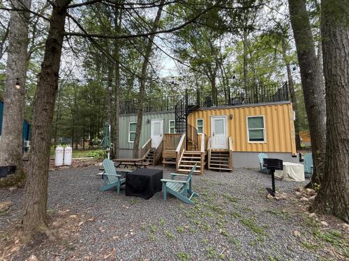 a tiny house in the woods with chairs and trees at Camptel Poconos in Albrightsville