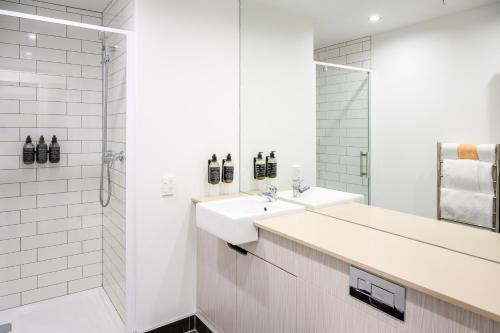 a white bathroom with two sinks and a shower at Boulcott Suites in Wellington