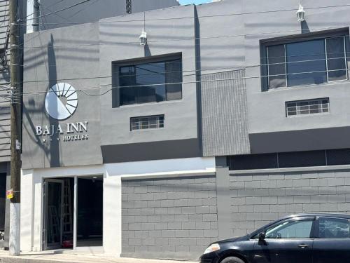 a building with a car parked in front of it at Baja Inn Hoteles La Mesa in Tijuana