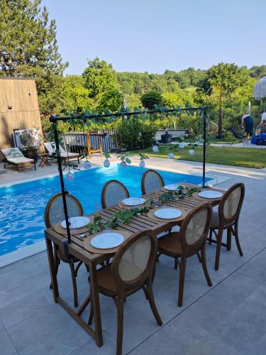 a wooden table with chairs in front of a pool at WoodEscape house in Petrovaradin