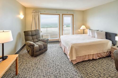 une chambre d'hôtel avec un lit, une chaise et une fenêtre dans l'établissement Oceanfront Fireplace Suite - Full Kitchen - Pool & Hot Tub, à Lincoln City