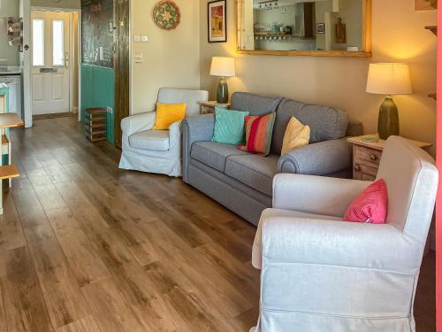 a living room with a couch and two chairs at Kippy Cottage in Porthtowan