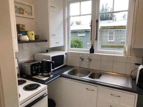 a small kitchen with a sink and a microwave at Guesthouse on Plummers Point in Whakamarama