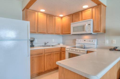a kitchen with wooden cabinets and a white refrigerator at Stunning Ocean View Suite - Heated Indoor Pool and Hot Tub in Lincoln City