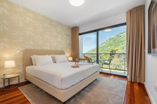 リベイラ・ブラーヴァにあるAtlantic Pebble Villaのベッドと大きな窓のある寝室