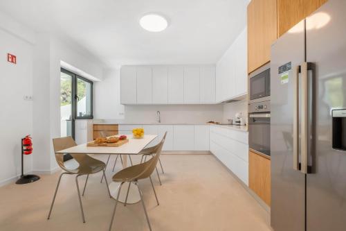 a kitchen with a table and chairs and a refrigerator at Atlantic Pebble Villa in Ribeira Brava
