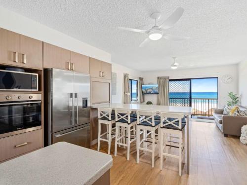 a kitchen with a bar with a view of the ocean at Palm Breeze - Hosted by Burleigh Letting in Gold Coast