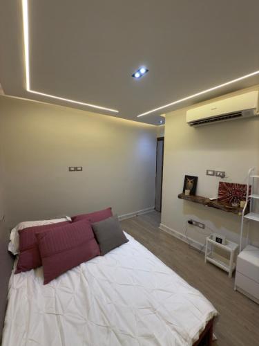 a bedroom with a large white bed with red pillows at Lovely One-bedroom Villa in Sharm El Sheikh