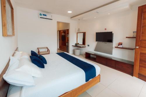 a bedroom with a bed with blue pillows and a television at Hotel Ninfa in Puerto Ayora