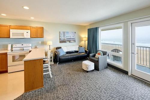 a kitchen and a living room with a couch and a table at Oceanfront Family Suite - Full Kitchen - Beach Access - Pool & Hot Tub in Lincoln City