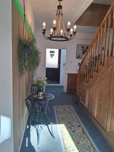 a hallway with a table and stairs with a chandelier at Crown House Studio Apartment in Birmingham