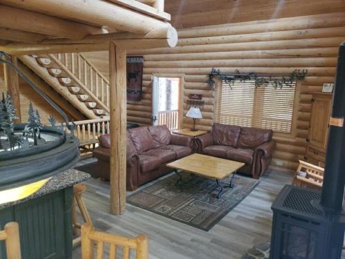 a living room with leather furniture in a log cabin at Summer Adventure Awaits! Hidden Pines- Yellowstone in Island Park