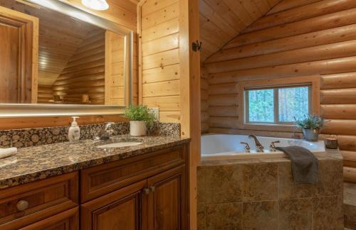 a bathroom with a tub and a sink in a log cabin at Summer Adventure Awaits! Hidden Pines- Yellowstone in Island Park