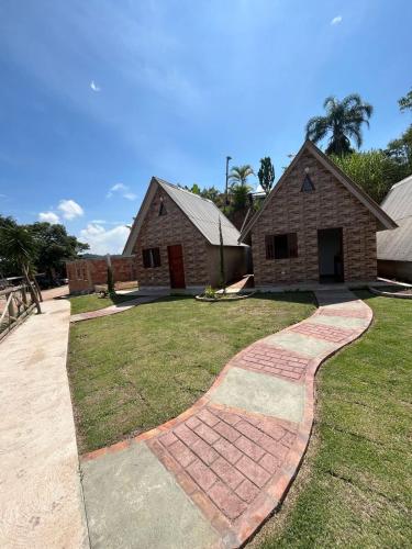 a house with a brick walkway in front of a yard at Chalés Paraíso Guararema 4 in Guararema