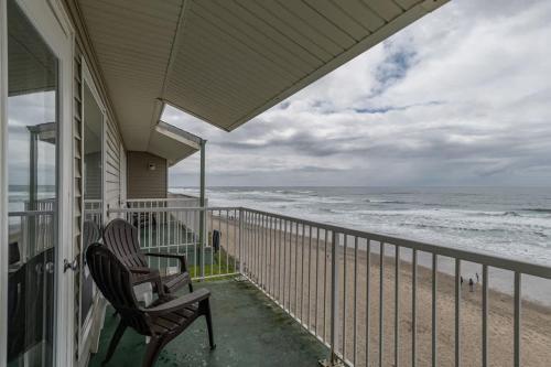 two chairs sitting on a porch looking at the ocean at Beachfront Family Suite - Ocean View - Full Kitchen in Lincoln City