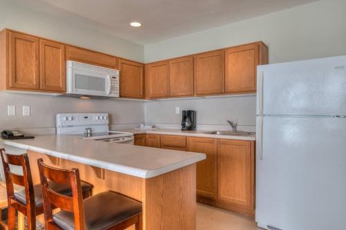 a kitchen with wooden cabinets and a white refrigerator at Beachfront Family Suite - Ocean View - Full Kitchen in Lincoln City