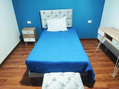 a blue bedroom with a bed with a blue bedspread at Pieza Amoblada 2 in Calama