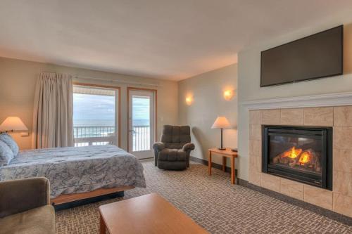 a hotel room with a bed and a fireplace at Stunning Oceanfront Suite - Sleeps Six - Top Floor - Heated Pool & Hot Tub Access in Lincoln City