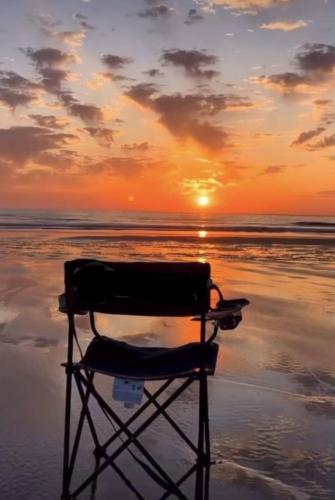 a chair sitting on the beach at sunset at Villa Maya House - Cap Zbib in Banī ‘Aţāʼ