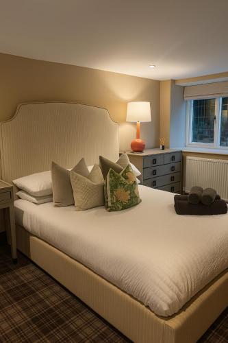 a bedroom with a large bed with pillows and a window at North Cottage - A Stylish Family Retreat Once Owned by Beatrix Potter in Bowness-on-Windermere