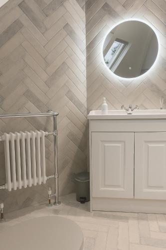 a bathroom with a white tub and a mirror at North Cottage - A Stylish Family Retreat Once Owned by Beatrix Potter in Bowness-on-Windermere