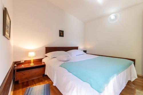 Un dormitorio con una cama blanca grande y una mesa en Seaside house for families with children Ivan Dolac, Hvar - 140, en Ivan Dolac