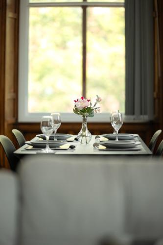 a table with glasses and a vase of flowers on it at Double story Suite in Rochdale in Rochdale