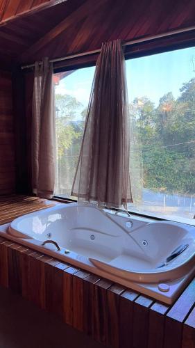a bath tub in a room with a large window at Emma Cabana Chalé Blumenau in Blumenau
