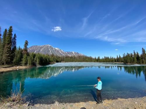 a man standing in front of a large lake at Twin Cabins-Trout and Grayling in Cantwell