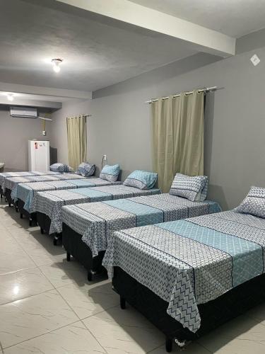 a group of beds lined up in a room at Hostel do Porto in Queimada