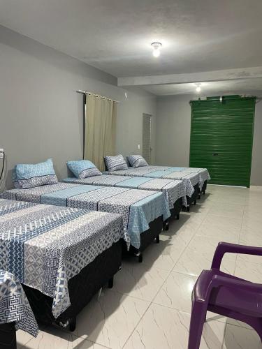 a row of beds in a room with a green door at Hostel do Porto in Queimada