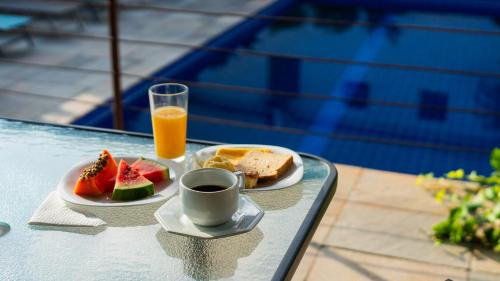a tray with a plate of fruit and a glass of orange juice at Hotel do Sol Executive in São Sebastião